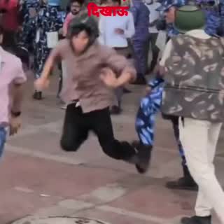 Still from the clip: a man running from personnel in riot gear as another person falls to the ground.