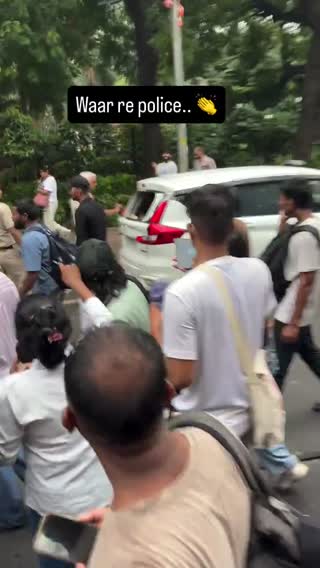 Still from the clip: a street scene with police and parked vehicles.