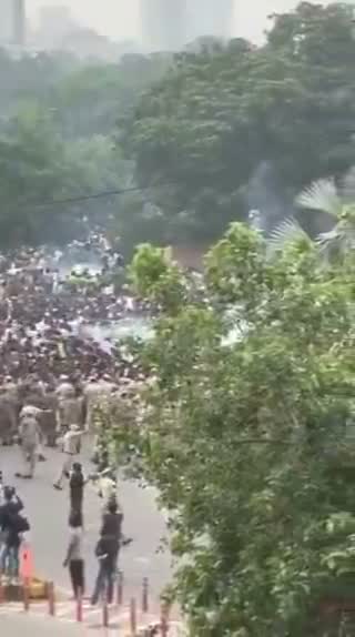 Still from the clip: a crowd on a road seen from above, with smoke drifting across it.